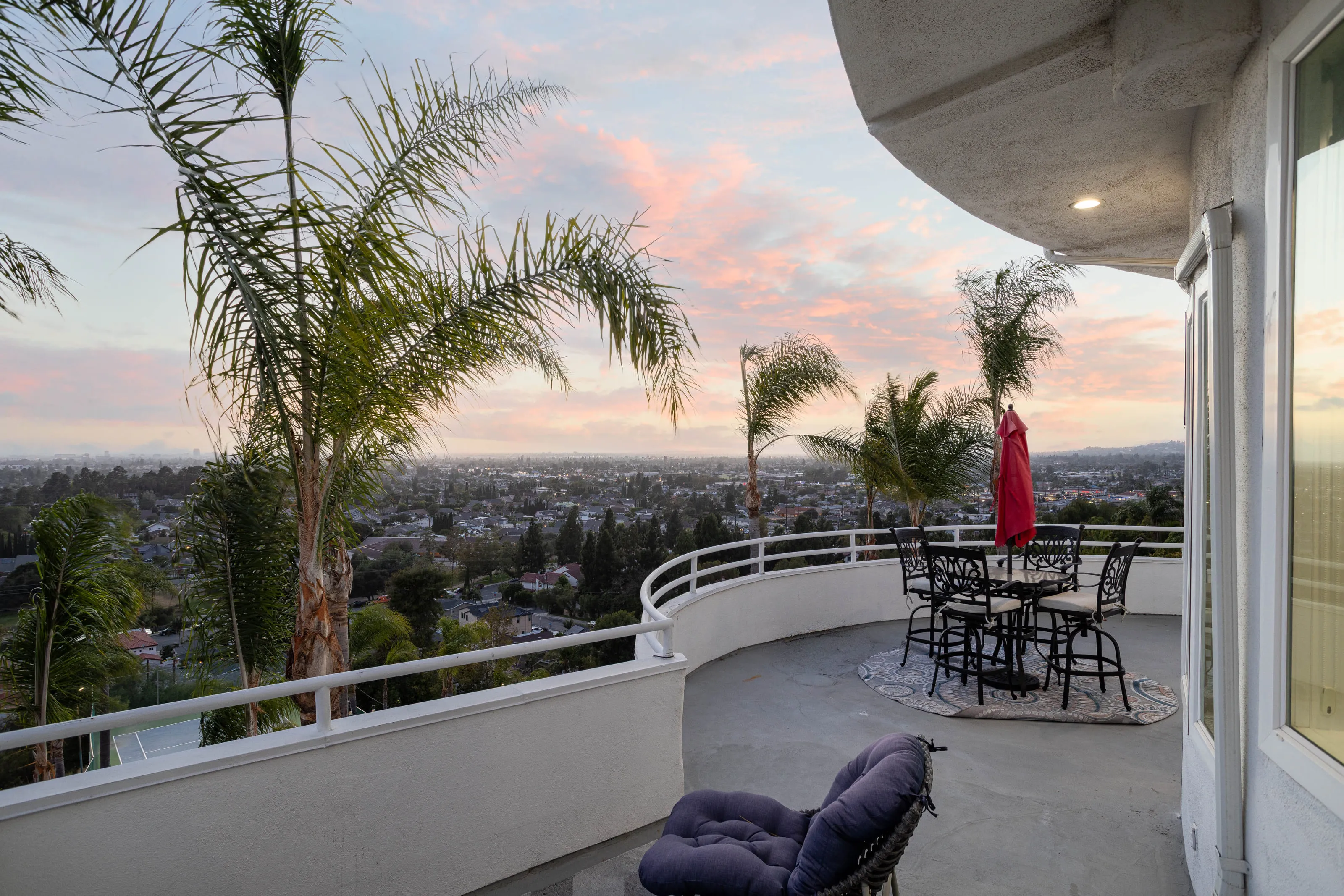 The curved balcony at sunset, palms framing the county below