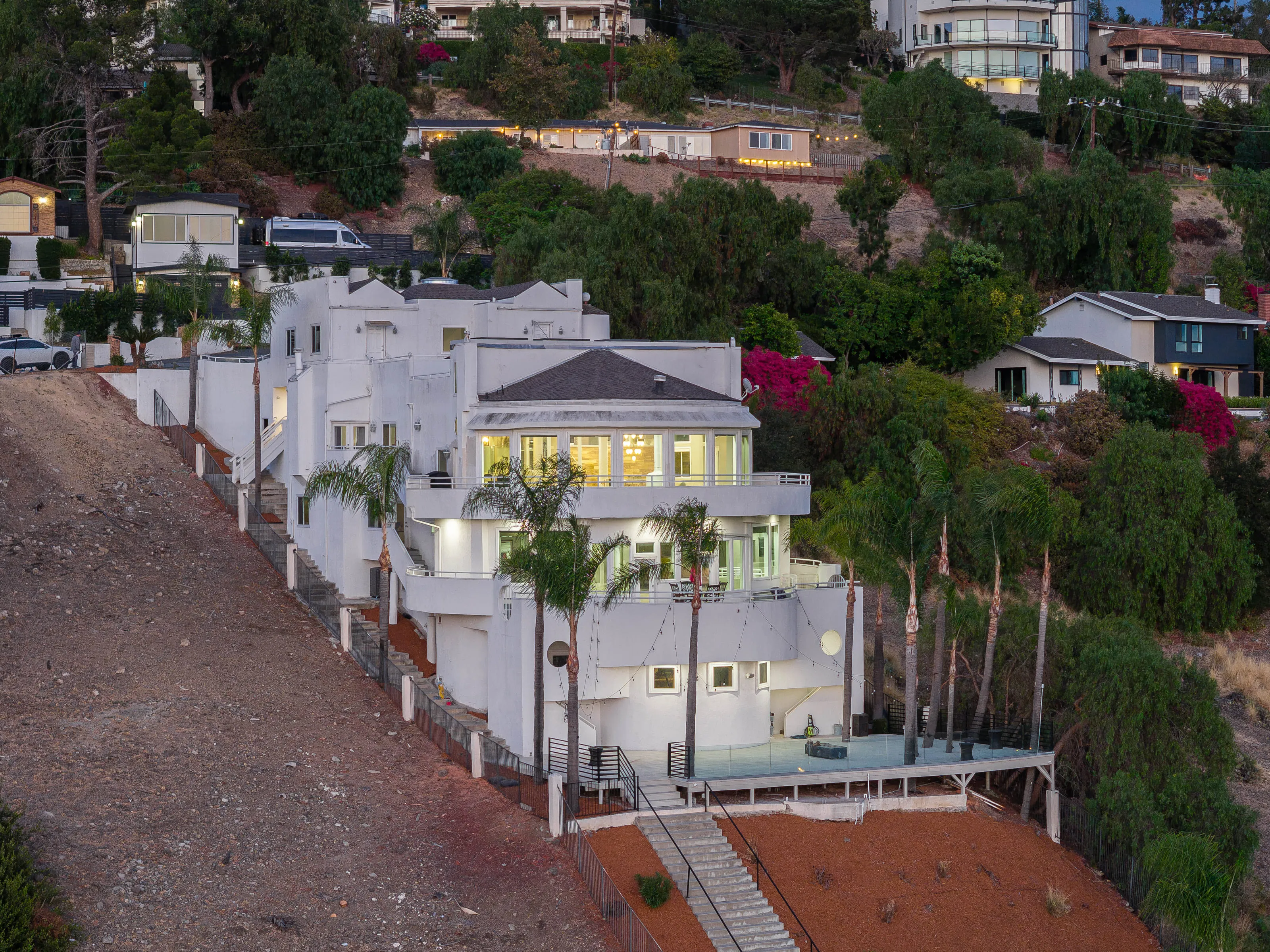 The whole house lit up at dusk on its hillside terraces