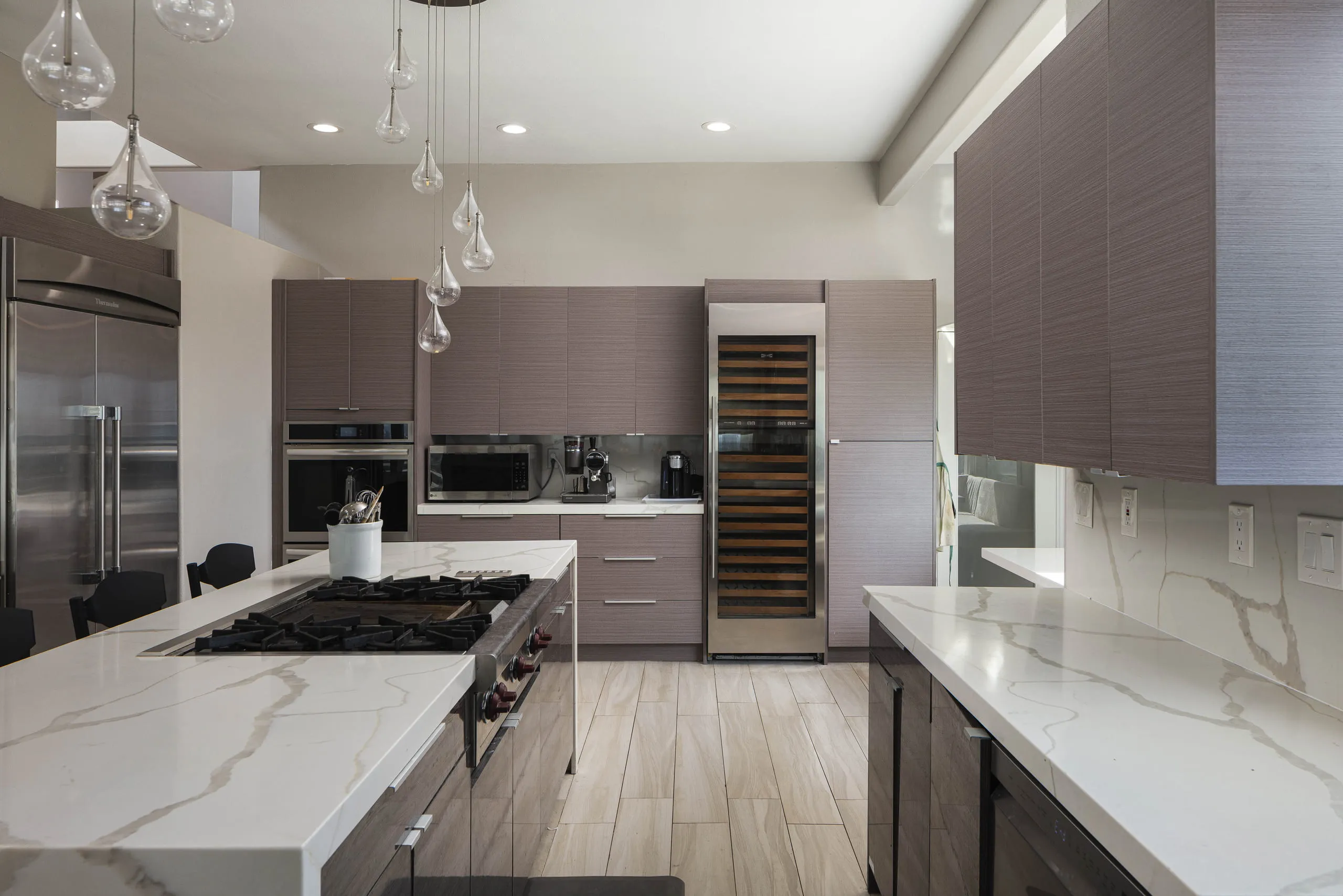 Kitchen with a marble waterfall island, professional range, and full-height wine column